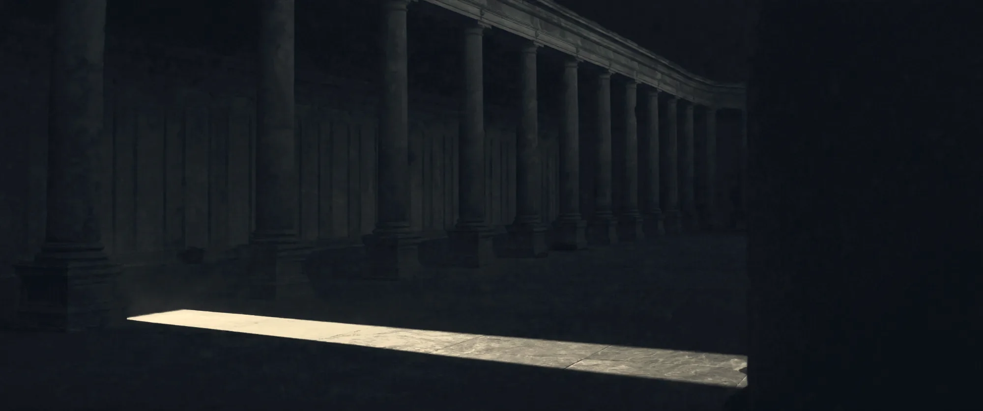 A colonnade of dark stone columns crossed by a shaft of light